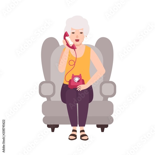 Old lady, elderly woman or granny sitting in cozy armchair and talking on pho...