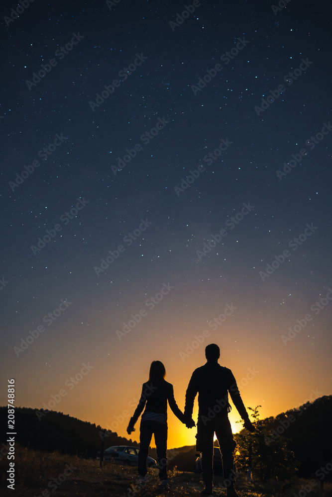 Silhouette of young couple holding hands under stars. The concept on the theme of love. romantic evening together, sunset, vertical photo Silhouette of young couple holding hands under stars. The concept on the theme of love. romantic evening together, sunset, vertical photo
