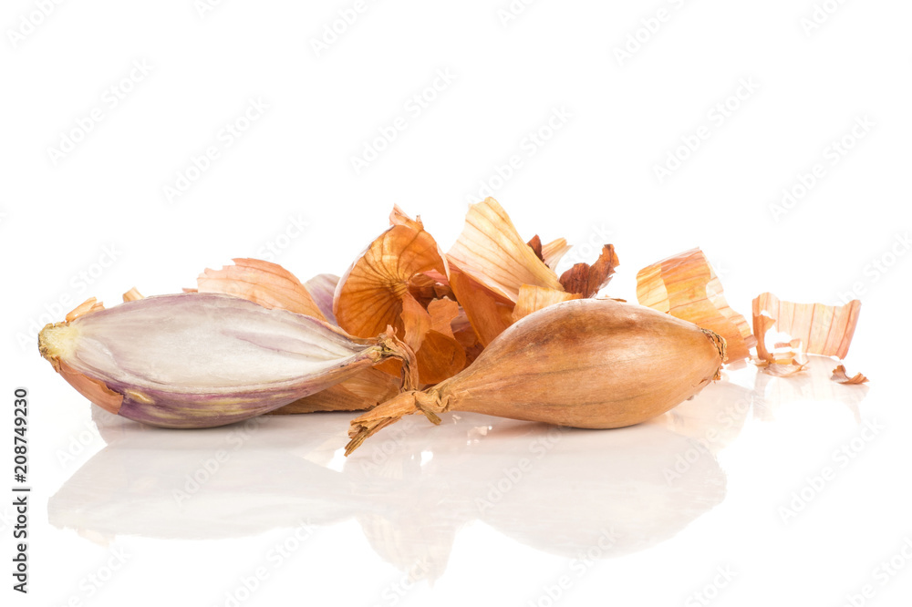 One shallot with sliced half in front of golden husk stack isolated on white background. One shallot with sliced half in front of golden husk stack isolated on white background.
