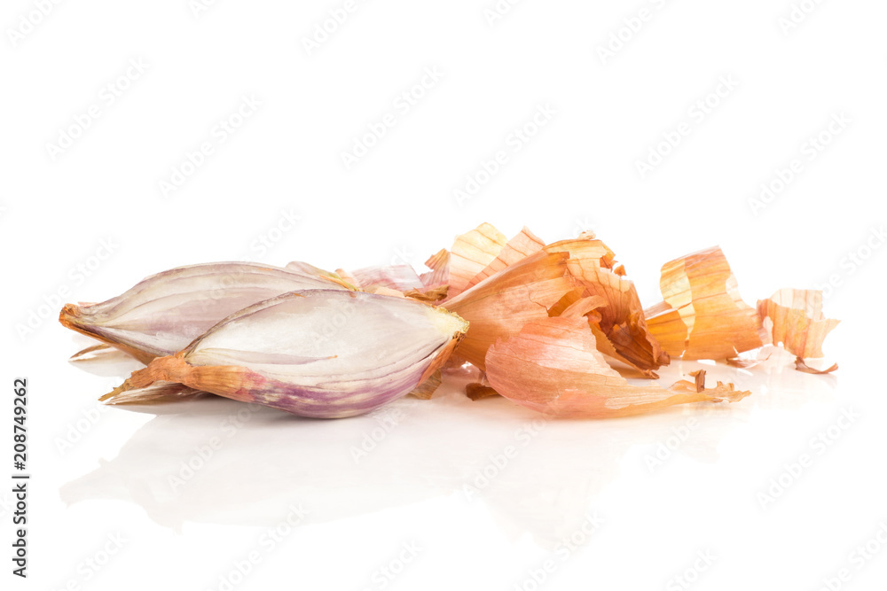 Two sliced shallot halves in front of golden husk stack isolated on white background.