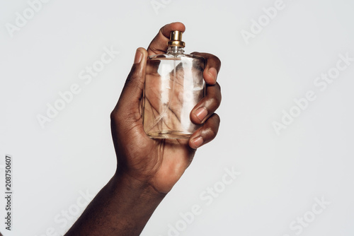 Hand of Afro American man holding perfume.