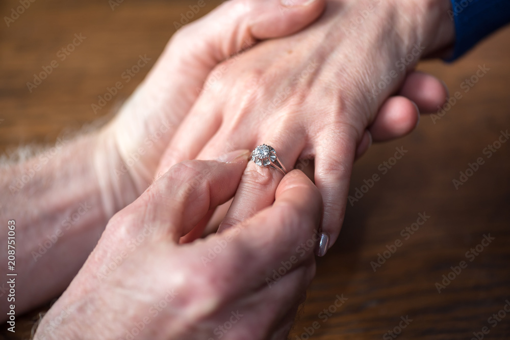 Man putting a ring on woman's finger Man putting a ring on woman's finger