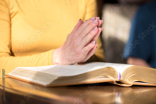 Woman praying with her hands over the bible