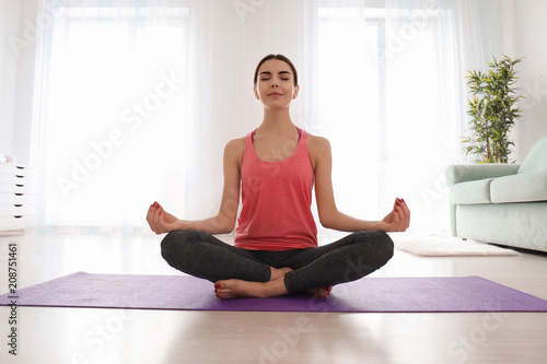 Beautiful young woman practicing yoga in morning