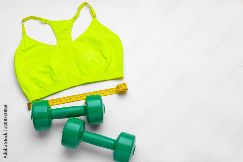 Composition with sportswear, dumbbells and measuring tape on white background Composition with sportswear, dumbbells and measuring tape on white background