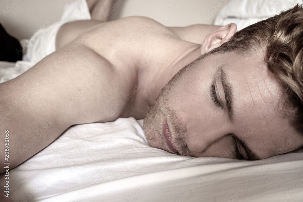 Handsome, sexy good looking man, first thing in the morning, sleeping in a bed with white sheets Handsome, sexy good looking man, first thing in the morning, sleeping in a bed with white sheets