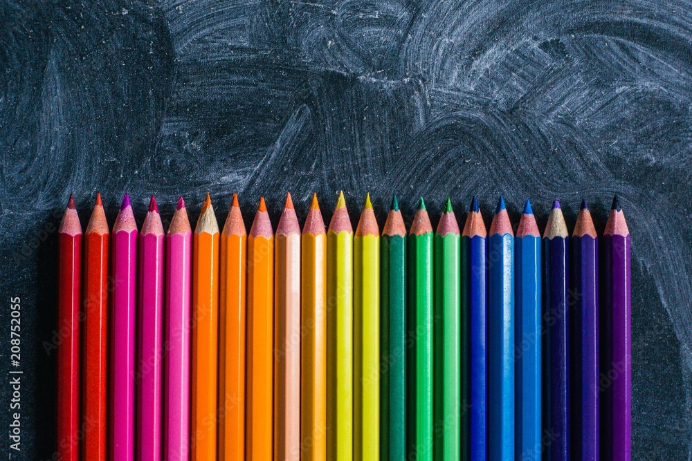 Colored pencils laid out on the chalkboard, top view Colored pencils laid out on the chalkboard, top view