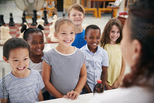 Group of smiling kids listening to teacher in science centre