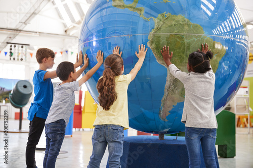 Group of school kids holding giant globe at a science centre