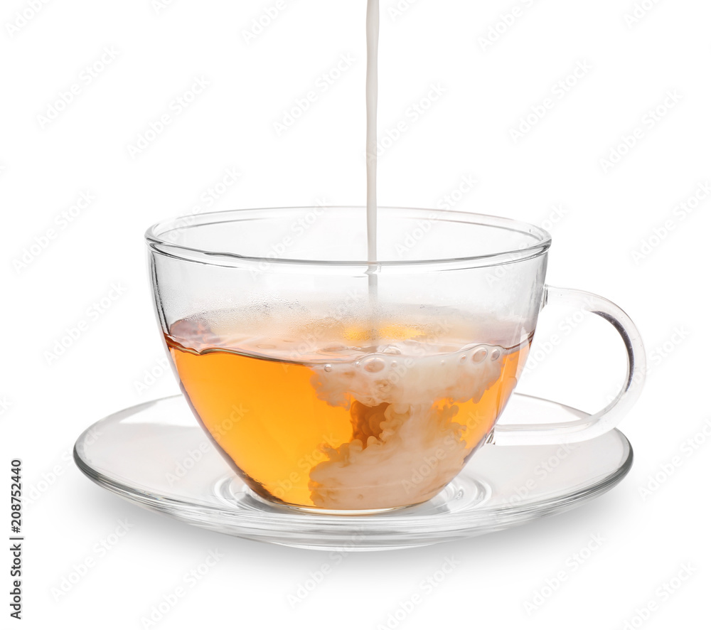 Pouring milk into glass cup with aromatic tea on white background Pouring milk into glass cup with aromatic tea on white background
