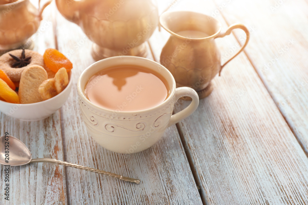 Cup of aromatic tea with milk on wooden table Cup of aromatic tea with milk on wooden table