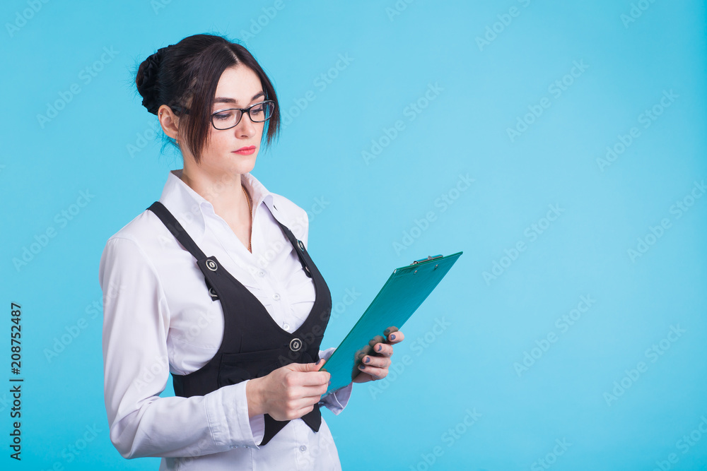 Portrait of young confident caucasian business woman with folder on blue background Portrait of young confident caucasian business woman with folder on blue background