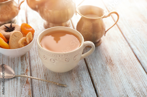 Cup of aromatic tea with milk on wooden table