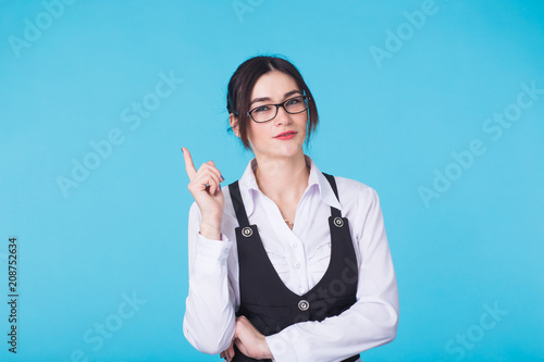 Young pretty girl holding finger up having idea and posing on blue background. photo