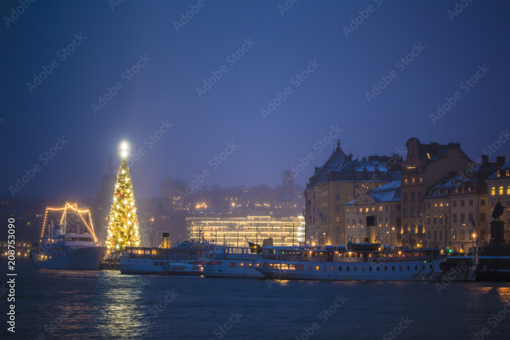 Beautiful winter scenery panorama of the Old Town (Gamla Stan) pier architecture with decorated gleaming Xmas Tree in Christmas and New Year holidays in Stockholm city, Night Sweden illuminated lights