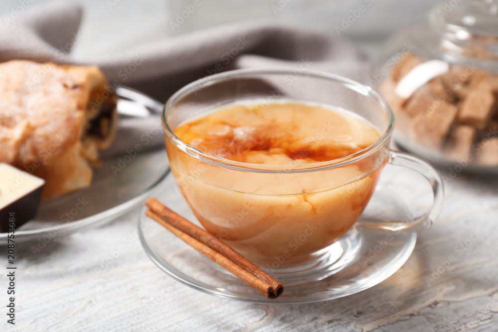 Cup of hot masala tea with cinnamon sticks on wooden table Cup of hot masala tea with cinnamon sticks on wooden table