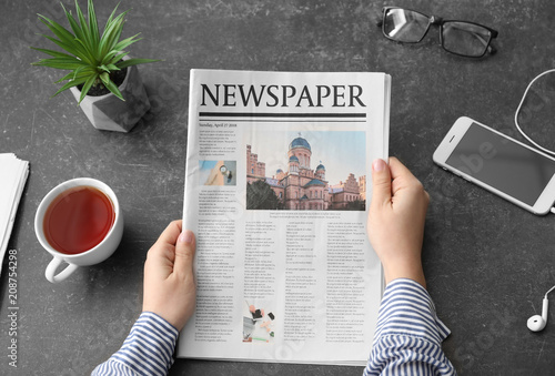 Fototapeta Woman reading morning newspaper at dark table