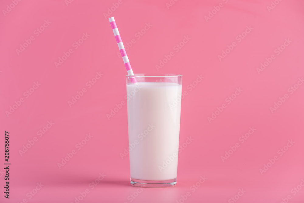 Glass of fresh milk with a straw on a pink background. Colorful minimalism. Healthy dairy products with calcium Glass of fresh milk with a straw on a pink background. Colorful minimalism. Healthy dairy products with calcium