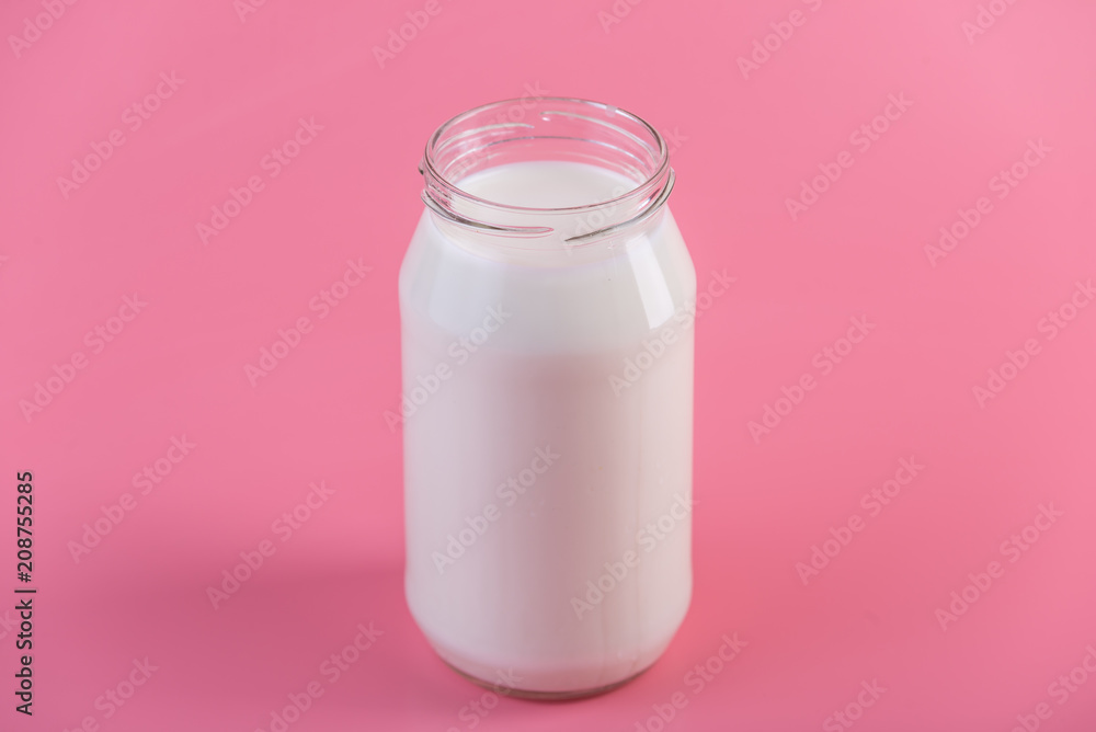 Glass bottle with fresh milk on pink background. Colorful minimalism. Healthy dairy products with calcium Glass bottle with fresh milk on pink background. Colorful minimalism. Healthy dairy products with calcium