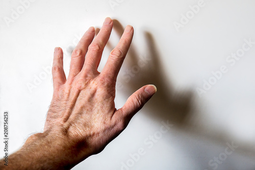 Man’s hand touching white wall - mental health concept.