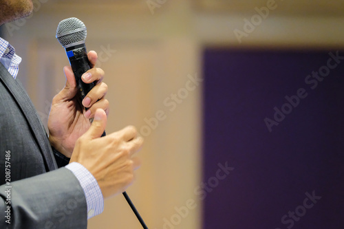 Businessman speaking with microphones in public meeting room at conference hall