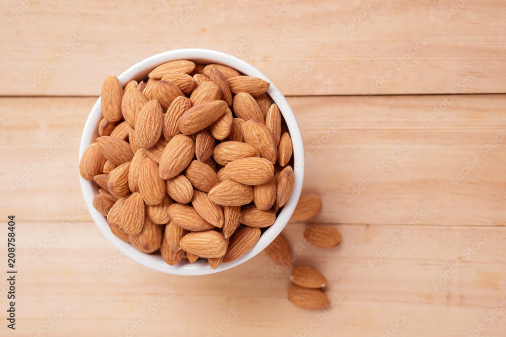 Almond nut in a ceramic bowl against wooden table Almond nut in a ceramic bowl against wooden table