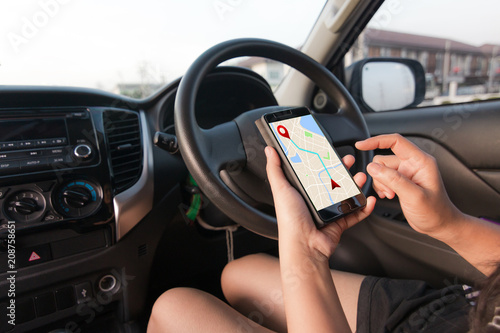 Hand of woman using smartphone with gps navigator map application in SUV car