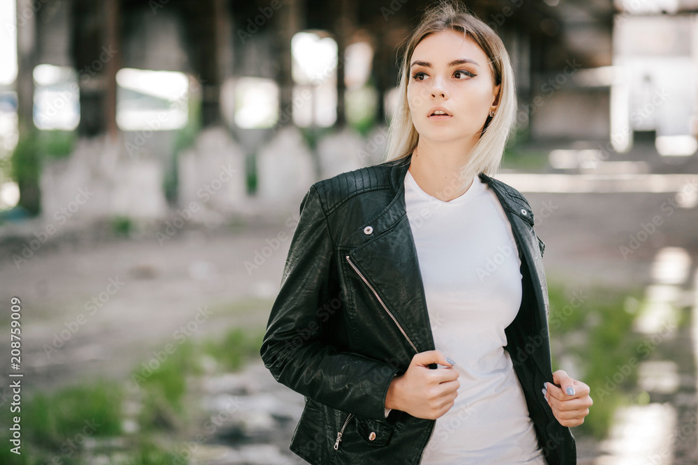 Girl wearing t-shirt and leather jacket posing against street , urban clothing style. Street photography Girl wearing t-shirt and leather jacket posing against street , urban clothing style. Street photography