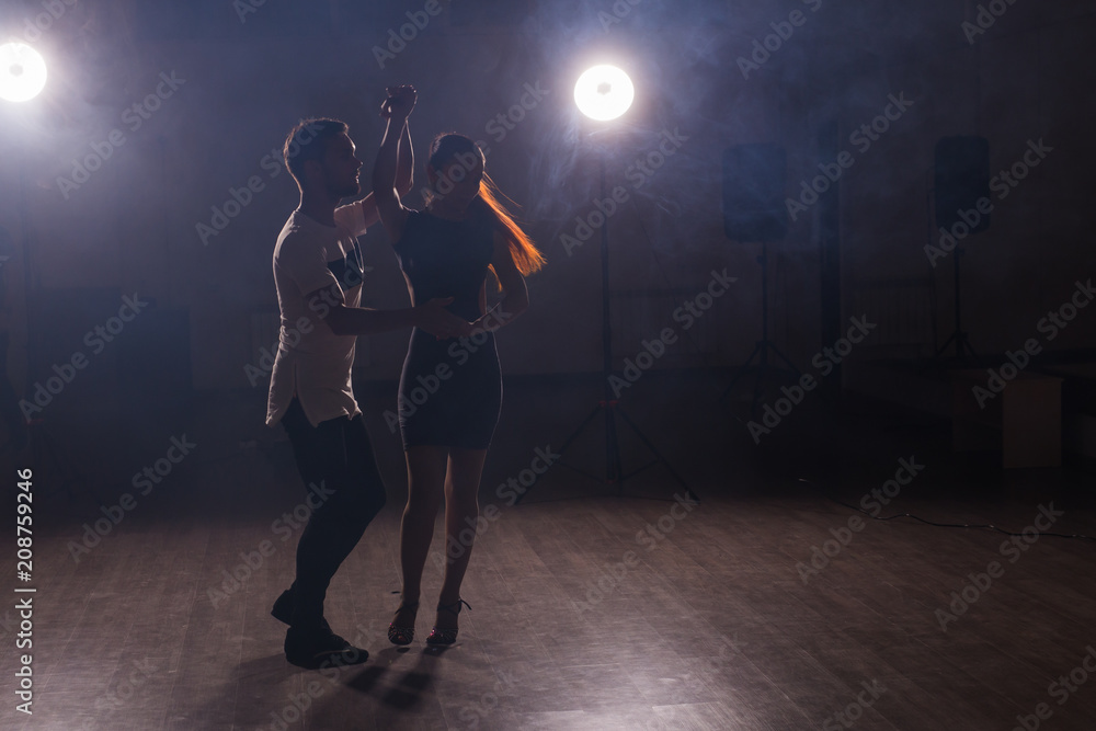 Skillful dancers performing in the dark room under the concert light and smoke. Sensual couple performing an artistic and emotional contemporary dance Skillful dancers performing in the dark room under the concert light and smoke. Sensual couple performing an artistic and emotional contemporary dance