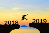 Happy New Year 2019 Men jump over silhouette mountains and sun