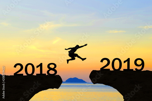 Happy New Year 2019 Men jump over silhouette mountains and sun