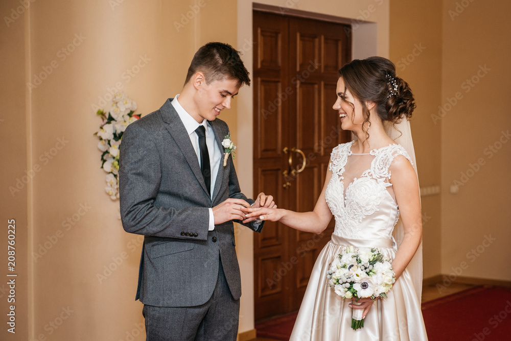 The bride and groom are exchanging wedding rings in the registry office