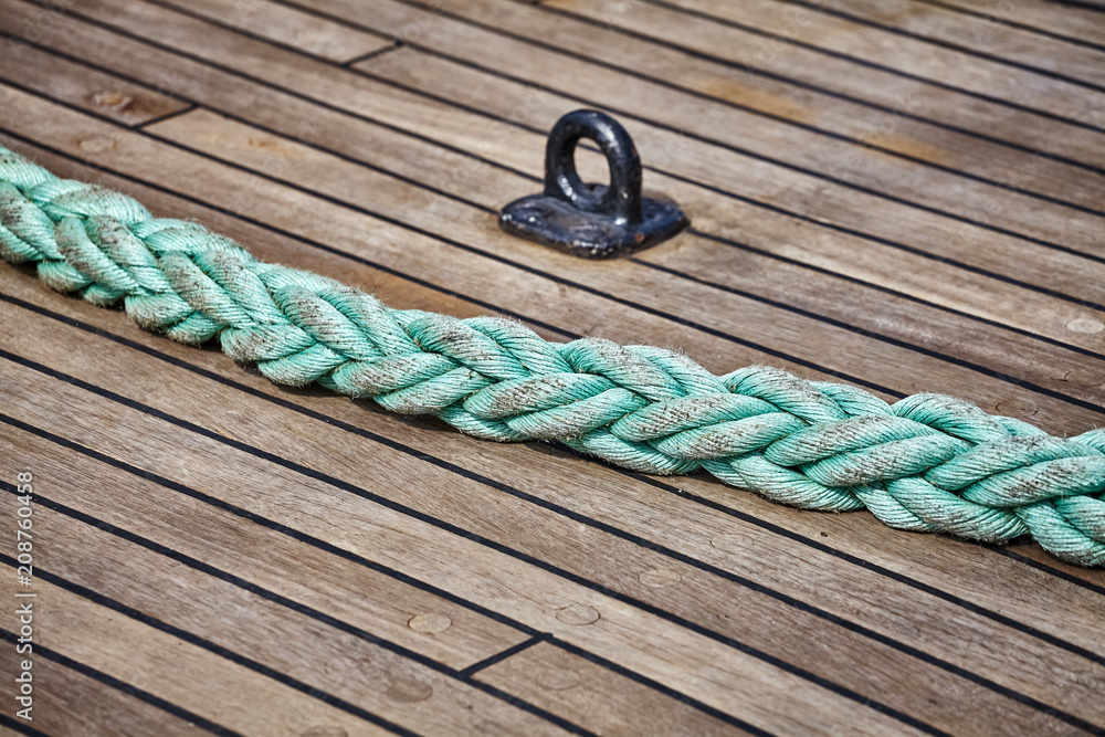 Green thick rope on an old sailing ship wooden deck, selective focus. Stock  Photo