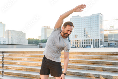 Smiling sportsman doing stretching exercises photo