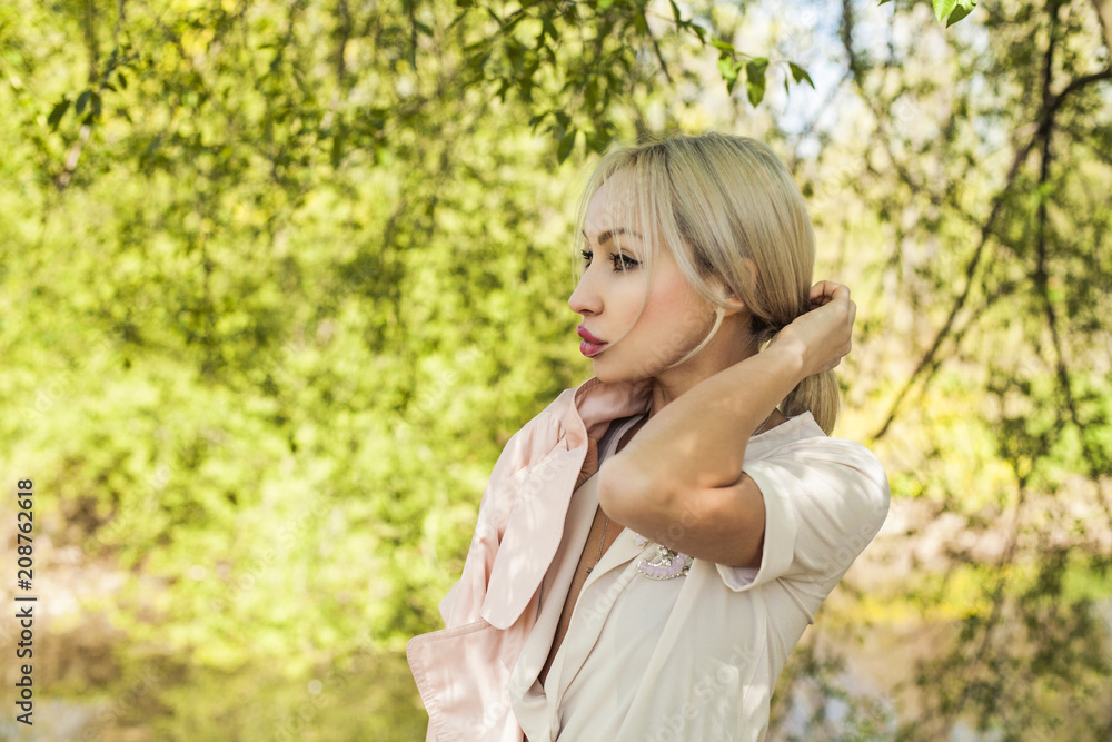 Blonde woman outdoors on green foliage leaves background Blonde woman outdoors on green foliage leaves background