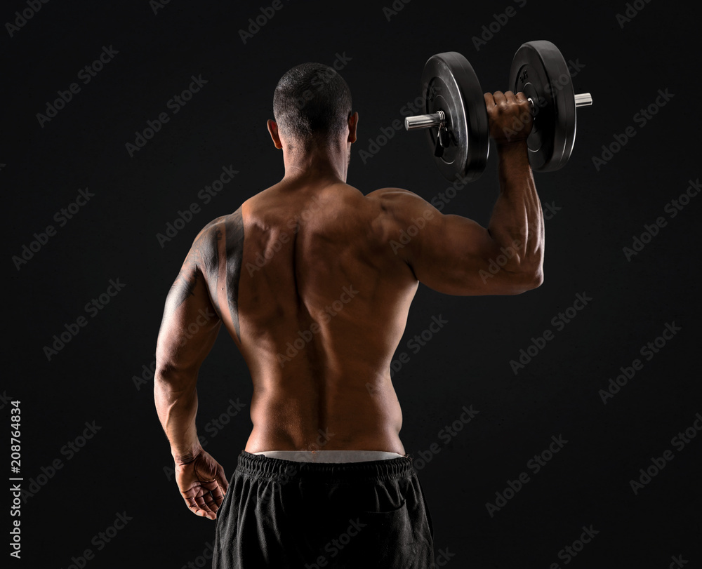 Strong handsome sport man making weightlifting and  exercising the shoulders on isolated black background