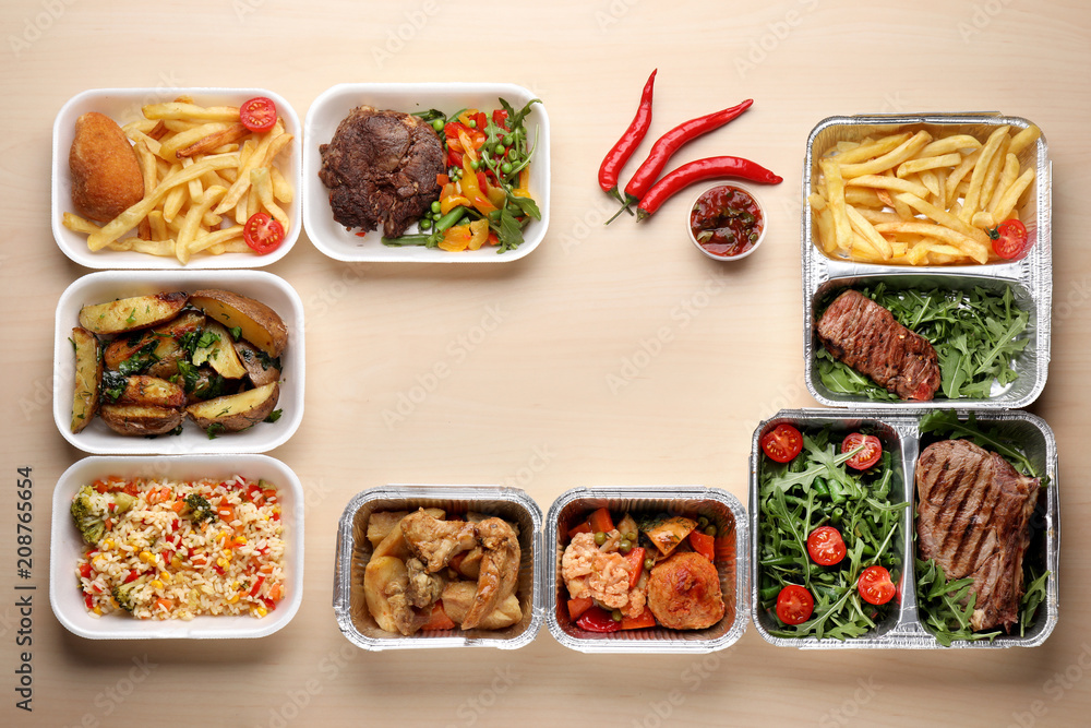 Different containers with delicious food on wooden table. Delivery service Different containers with delicious food on wooden table. Delivery service