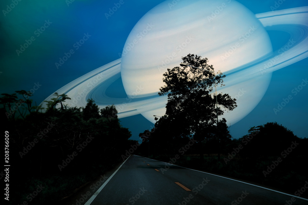 Fototapeta premium Saturn near earth on night sky over the country road