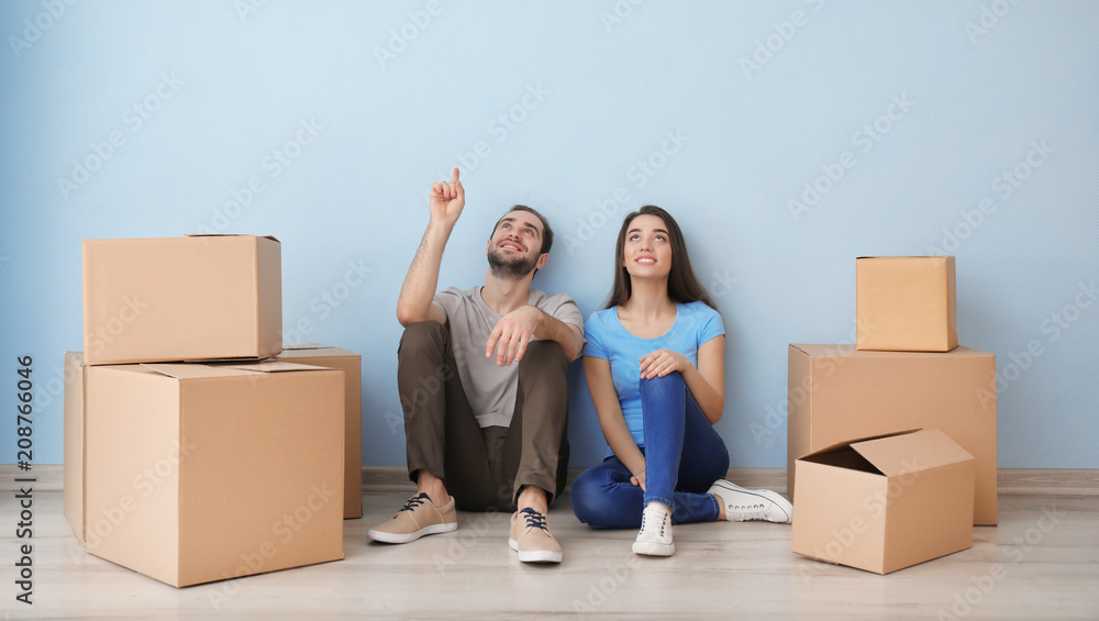 Young couple resting near boxes indoors. Moving into new house Young couple resting near boxes indoors. Moving into new house