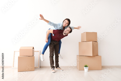 Young couple playing near boxes indoors. Moving into new house
