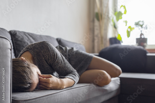 Pensive woman lying down on sofa photo