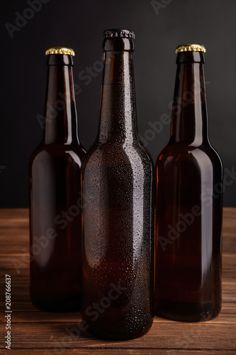 Fresh beer in glass bottles on table against dark background