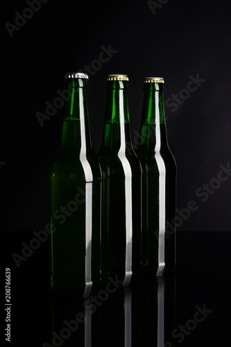 Fresh beer in glass bottles on black background