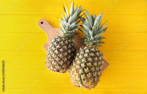 Tasty pineapples and board on wooden table