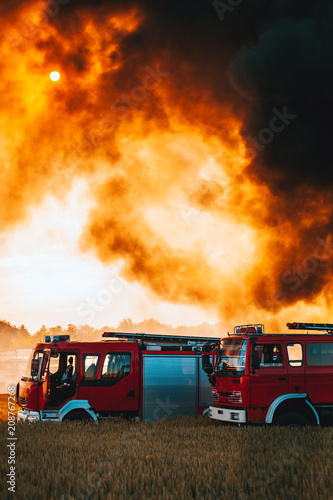 Fotografie, Tablou Red fire trucks in front of huge black smoke from the fire