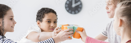 Photography Multicultural group of kids holding paper cups and toasting at a birthday party