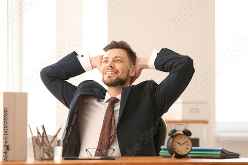 Happy businessman at table in office. Time management concept photo