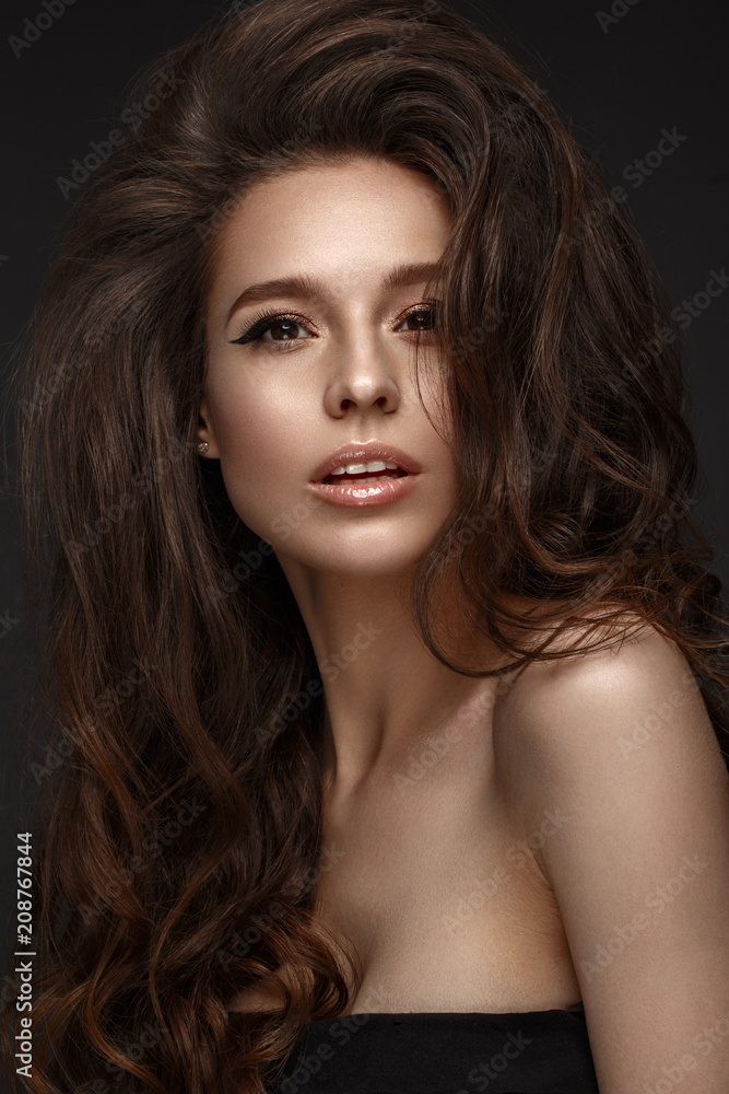 Beautiful brunette model with volume curls, classic makeup and sexy lips. The beauty of the face. Portrait shot in the studio. Beautiful brunette model with volume curls, classic makeup and sexy lips. The beauty of the face. Portrait shot in the studio.