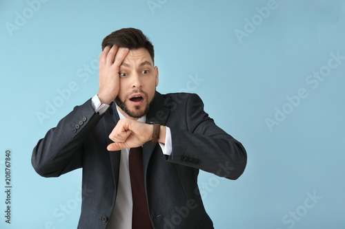 Man looking at wristwatch on color background. Time management concept