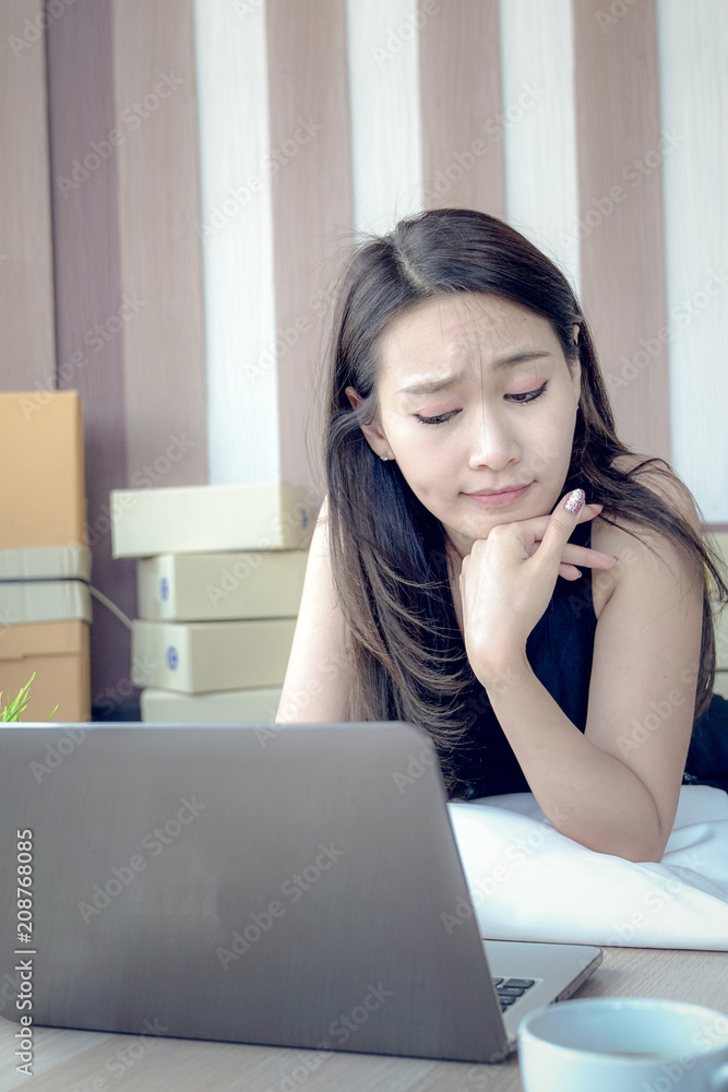 Young business owner of the SME start up company be moody from problem about customers in the online trading business with a computer laptop in the Home Office Young business owner of the SME start up company be moody from problem about customers in the online trading business with a computer laptop in the Home Office